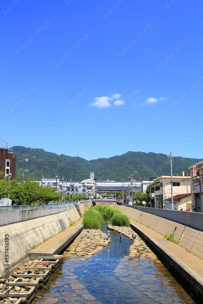 Obraz premium 初夏の河川敷で水遊びをする親子、神戸市灘区都賀川にて