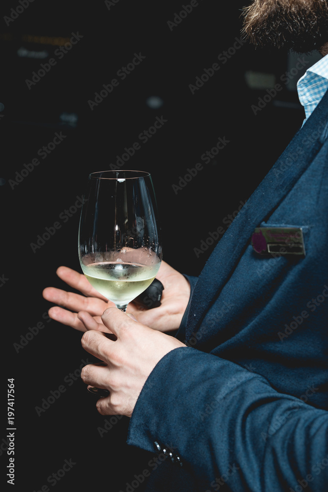 man holds glass of wine. people consider the color of the wine and try how it smells in different glasses man holds glass of wine. people consider the color of the wine and try how it smells in different glasses