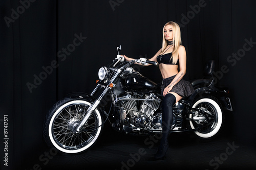 portrait of a beautiful blonde on a motorcycle on a black background  rocker