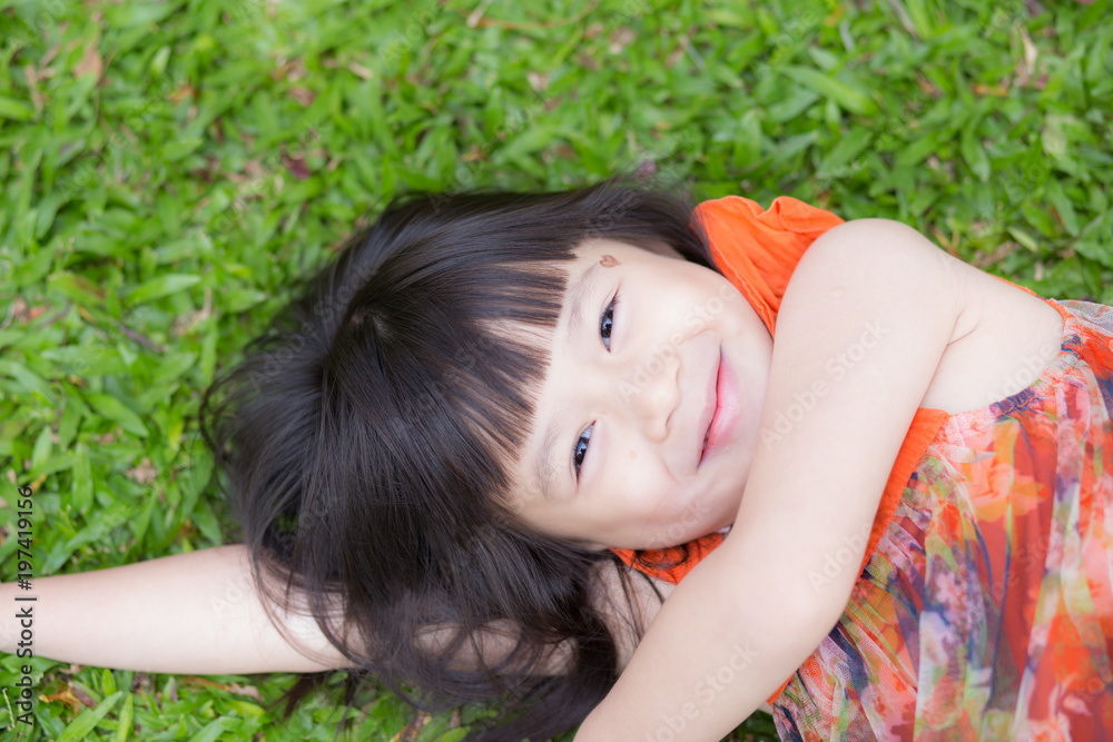 Beautiful portrait little girl asian of a smiling lying on green grass at the park, kid leisure and joyful in outdoor. Beautiful portrait little girl asian of a smiling lying on green grass at the park, kid leisure and joyful in outdoor.