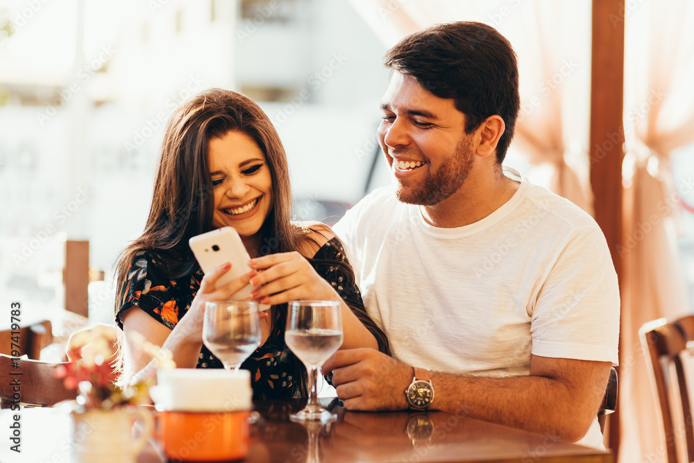Couple at restaurant looking at his smart phone