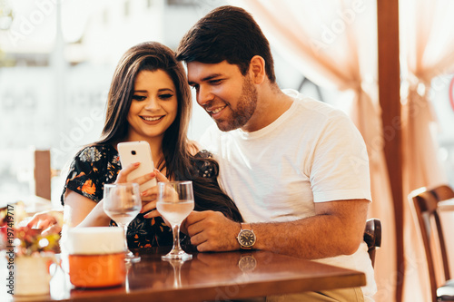 Couple at restaurant looking at his smart phone
