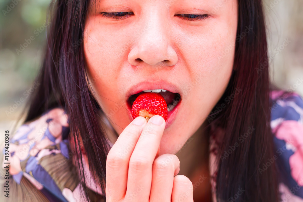 Long hair Asian women eating strawberry fruit, hand put one strawberry in to mouth Long hair Asian women eating strawberry fruit, hand put one strawberry in to mouth