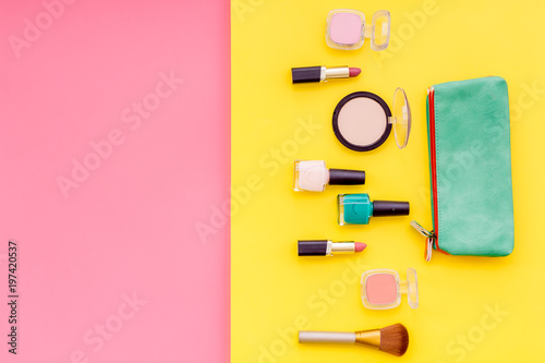 Women desk with decorative cosmetics for make up on pink and yellow background flat lay space for text