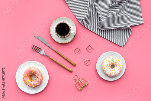 modern breakfast desing with sweet donut, coffee and flowers on woman pink desk background top view photo