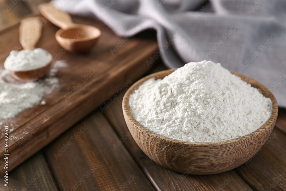 Wheat flour in bowl on wooden table Wheat flour in bowl on wooden table