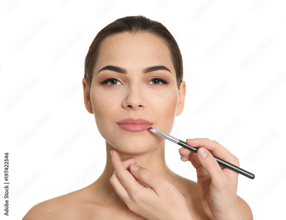 Visage artist applying makeup on woman's face against white background. Professional cosmetic products