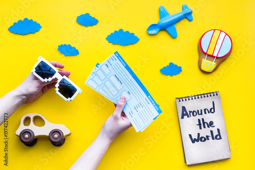 Travelling with child concept. Air balloon, car and plane. Around the world hand lettering in notebook on yellow background top view copy space