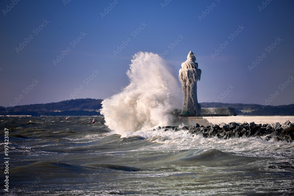 frozen lighthouse and pier on stormy winter day