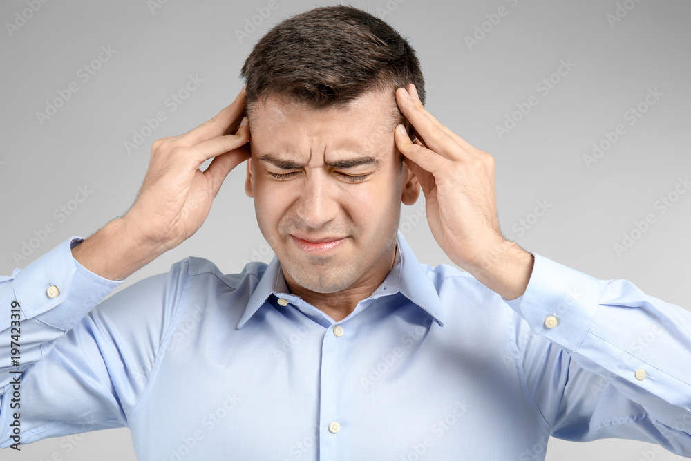 Young man suffering from headache on light background Young man suffering from headache on light background