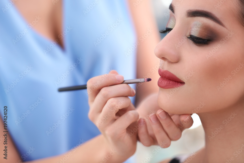 Professional visage artist applying makeup on woman's face in salon, closeup Professional visage artist applying makeup on woman's face in salon, closeup