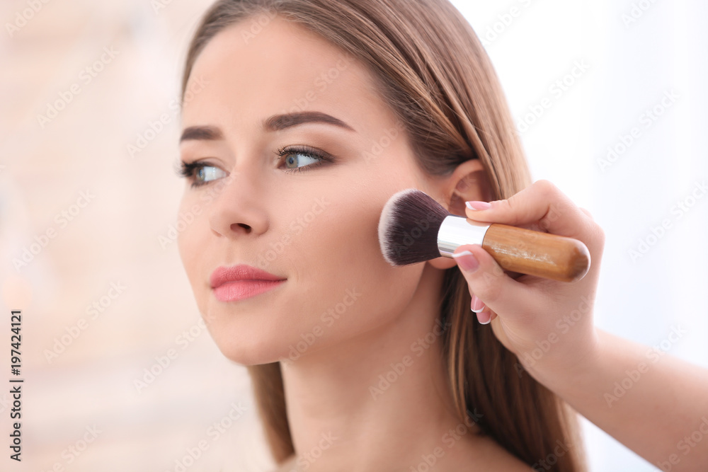 Professional visage artist applying makeup on woman's face in salon, closeup Professional visage artist applying makeup on woman's face in salon, closeup