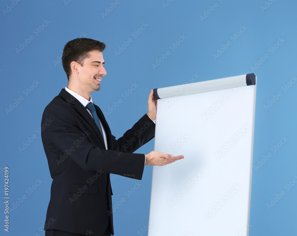 Business trainer giving presentation on flip chart board against color background Business trainer giving presentation on flip chart board against color background