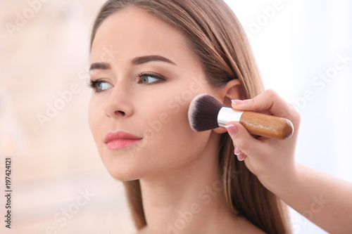Professional visage artist applying makeup on woman's face in salon, closeup