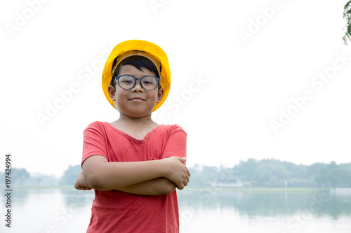 Asian boy dress like engineer stand and cross arms on his chest with garden background