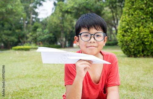 Asian boy in red t-shirt dress enjoy playing with a paper rocket with garden scene
