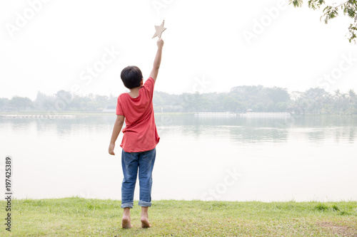 Asian boy in red t-shirt dress hold a kraft paper star with pond scene