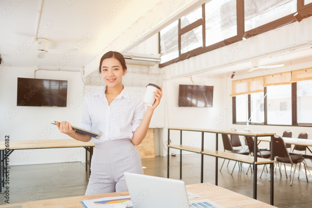Portrait of smiling pretty young business woman on workplace, Calculating the cost of postage of a small package, Small business enterprise concerns for online Shopping Portrait of smiling pretty young business woman on workplace, Calculating the cost of postage of a small package, Small business enterprise concerns for online Shopping