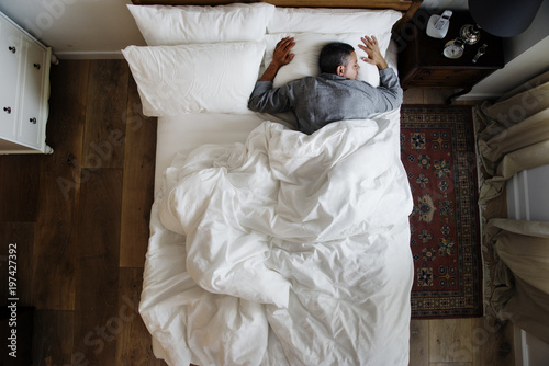 French man sleeping alone on bed