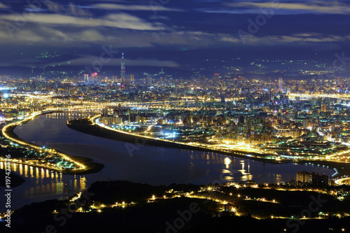 Aerial panorama of Taipei City in a blue gloomy night, with view of Kuandu plain, Tamsui River, downtown area and Taipei 101 tower in XinYi District, in evening twilight