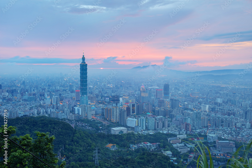 Fototapeta premium Aerial panorama of busy Taipei City at moody dusk with Taipei 101 in XinYi commercial area, Tamsui River and downtown area in twilight with beautiful rosy afterglow shining through heavy clouds 