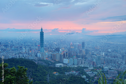 Aerial panorama of busy Taipei City at moody dusk with Taipei 101 in XinYi commercial area, Tamsui River and downtown area in twilight with beautiful rosy afterglow shining through heavy clouds 