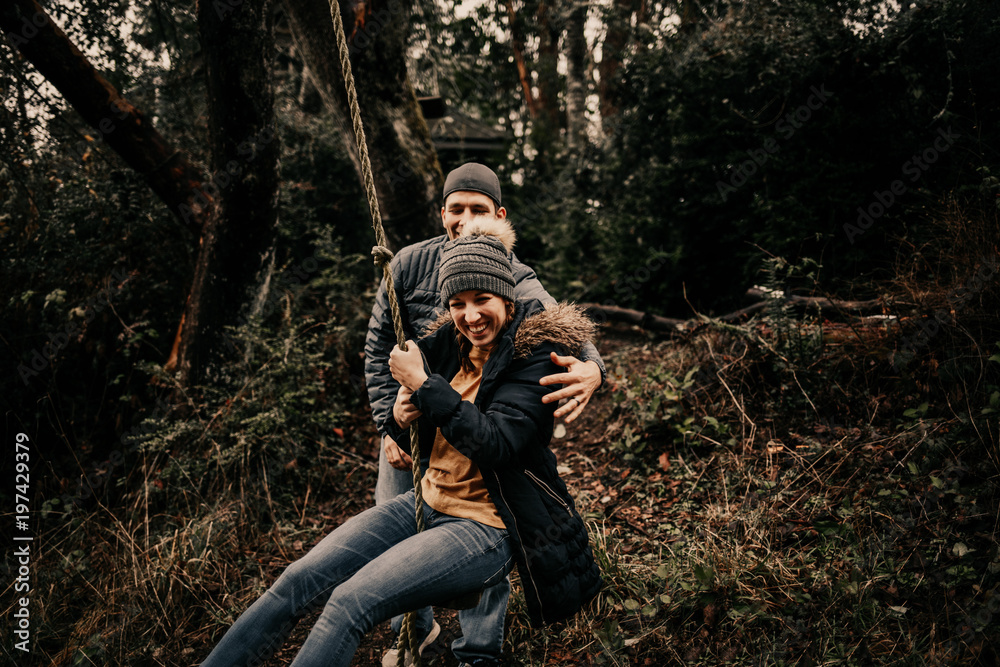 Happy couple swinging on forest rope swing Happy couple swinging on forest rope swing