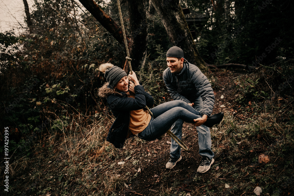 Happy couple swinging on forest rope swing Happy couple swinging on forest rope swing