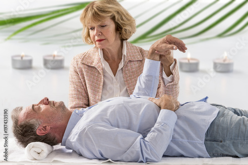 Obraz na płótnie Hypnotherapist holding her patients wrist in therapists officewith warm candle a
