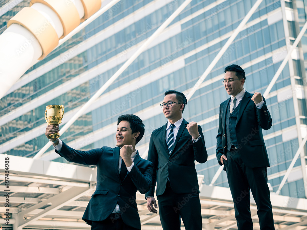 Happy Asian business people with golden trophy cup for their winner in ...