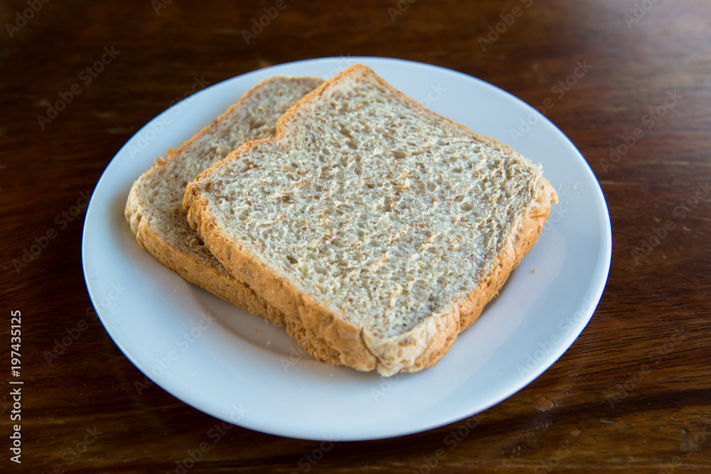 2 slices whole wheat bread, put on a white plate.