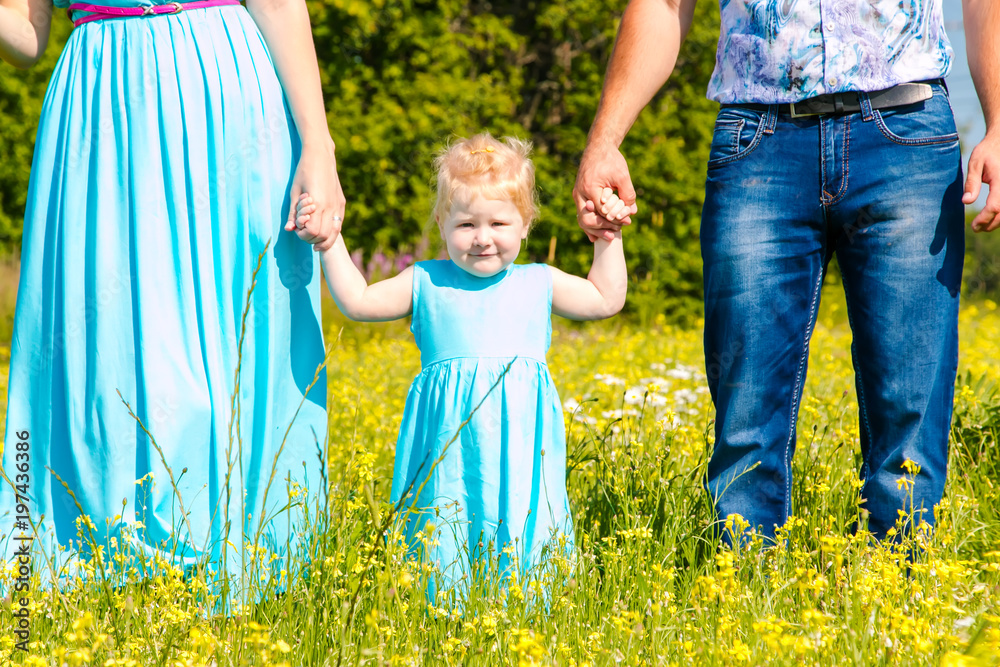 Young happy caucasian family with baby girl look at camera. celebration fathers day outdoors. hafving fun. Summer, green flowers field Young happy caucasian family with baby girl look at camera. celebration fathers day outdoors. hafving fun. Summer, green flowers field
