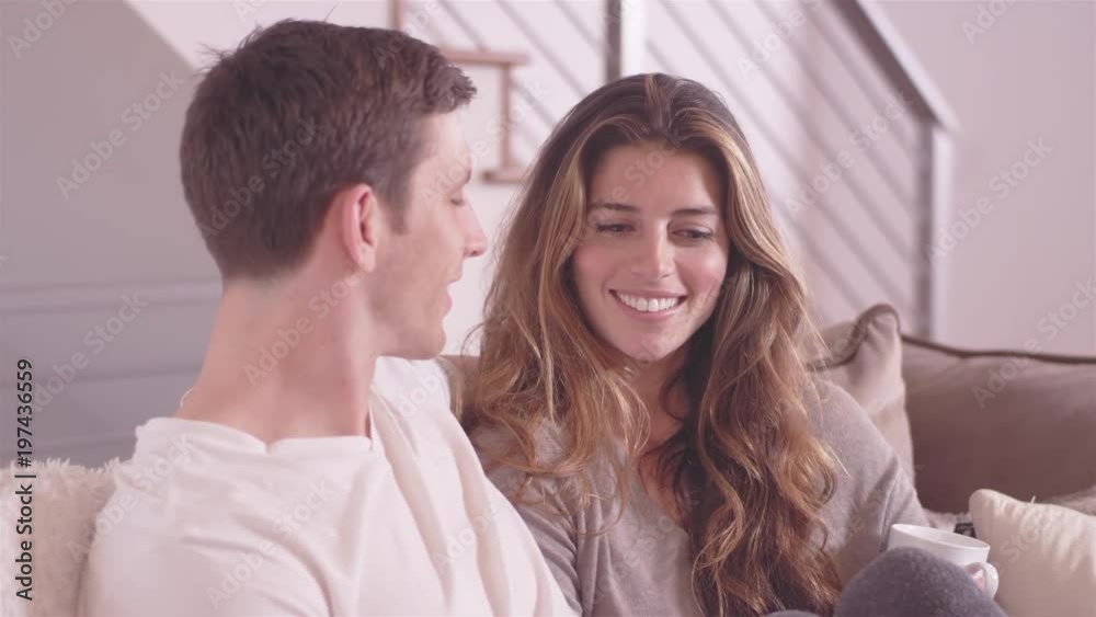 Young attractive couple having a conversation while relaxing in their living room Young attractive couple having a conversation while relaxing in their living room