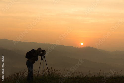 Silhouette of a traveler taking photo sunup in the mountains
