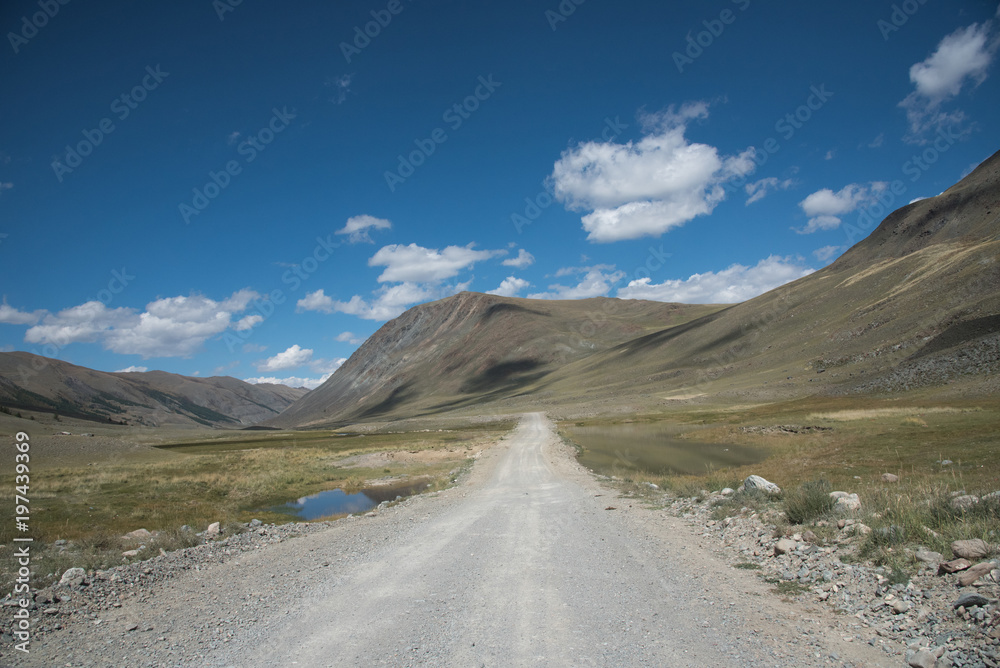 Fototapeta premium Wildlife Altai. The road, mountains and sky with clouds in summer