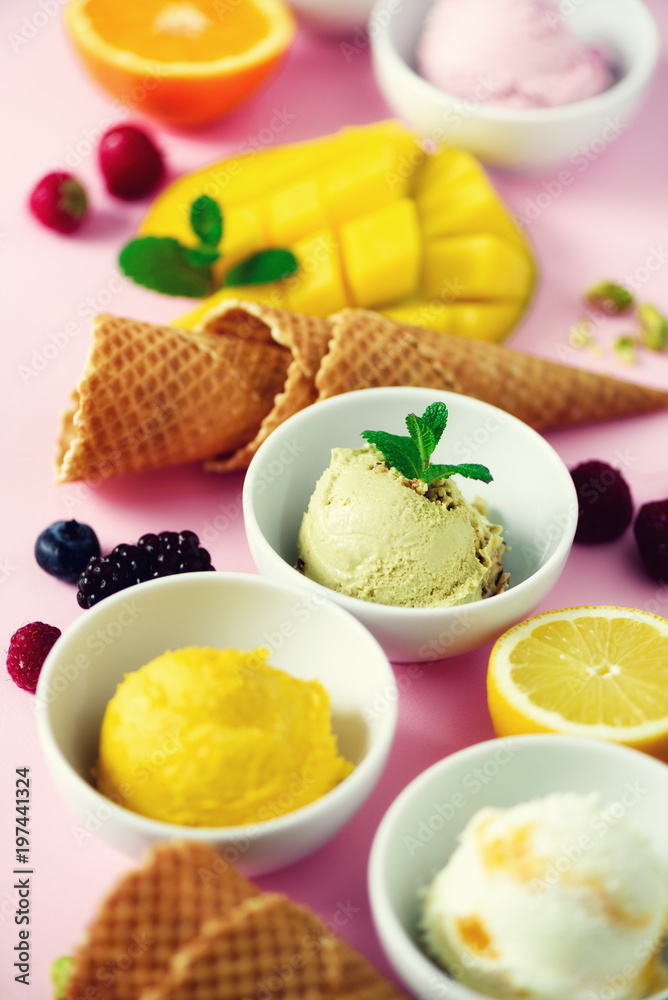 Ice cream balls in bowls, waffle cones, berries, orange, mango, lemon, mint, pistachio on pink shabby chic background. Colorful collection, summer concept Ice cream balls in bowls, waffle cones, berries, orange, mango, lemon, mint, pistachio on pink shabby chic background. Colorful collection, summer concept