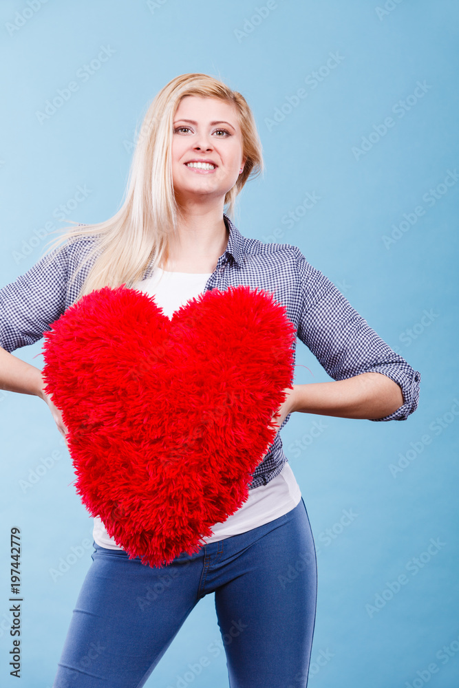 Happy woman holding red pillow in heart shape Happy woman holding red pillow in heart shape