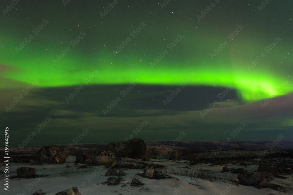 Northern lights, aurora over hills and tundra in the winter.