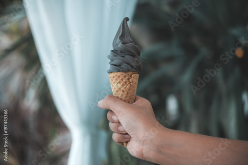 A hand holding charcoal ice cream cone with blur background © Farknot Architect