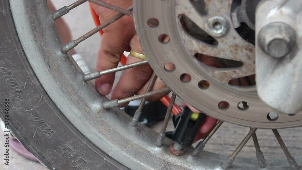 Hands pump air into motorcycle tire Hands pump air into motorcycle tire