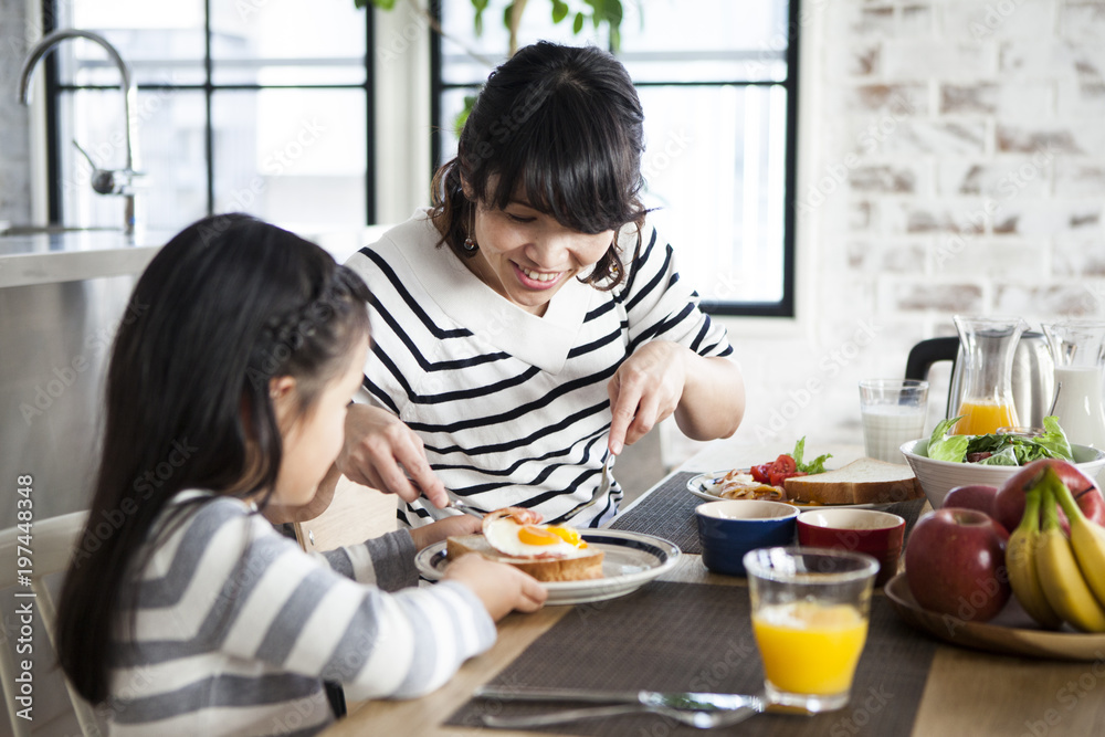 ママが娘の食事を取り分けている。仲良し親子。 ママが娘の食事を取り分けている。仲良し親子。
