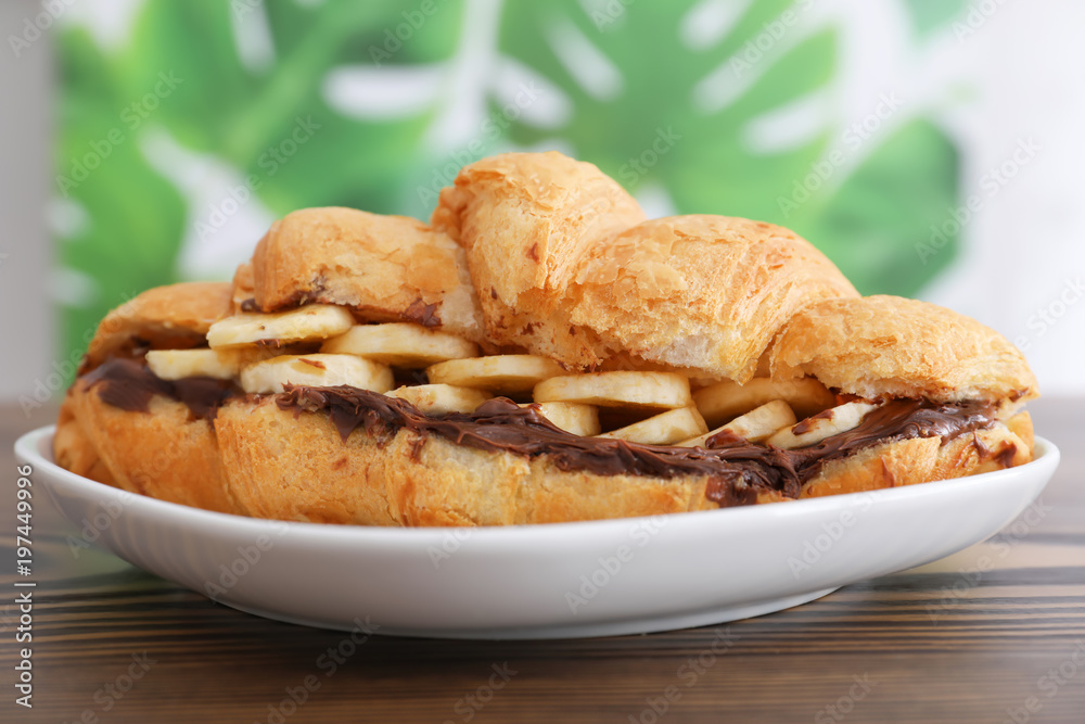 Tasty croissant with banana and chocolate sauce on plate, closeup Tasty croissant with banana and chocolate sauce on plate, closeup
