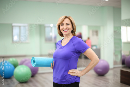 Mature woman with mat in gym