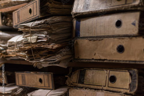 Fotografi Old dusty stack of papers, files, documents on the shelves of archive room