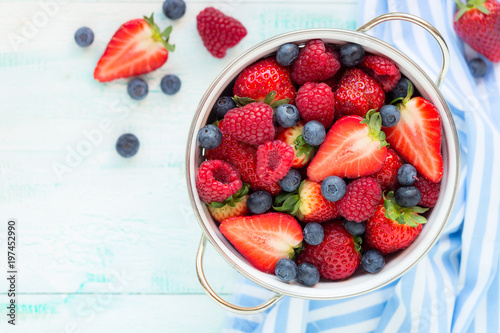 Fotografija Fresh berries - strawberries, raspberries and blueberries - in a while colander
