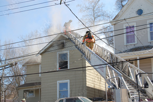 firemen fighting a roof fire on a quiet neighborhood street