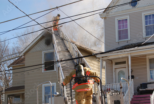 firemen fighting a roof fire on a quiet neighborhood street