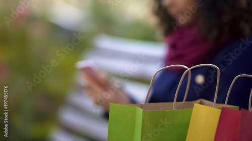 Colourful purchases, woman shopping online on background, using smartphone