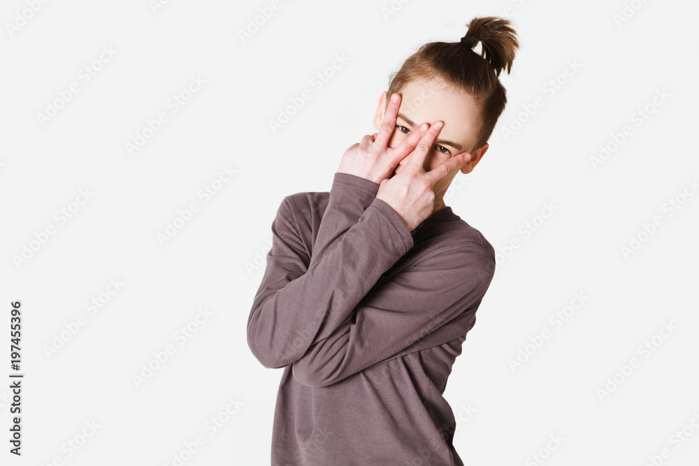 Portrait of a teenager boy showing peace signs with hands gray background Portrait of a teenager boy showing peace signs with hands gray background