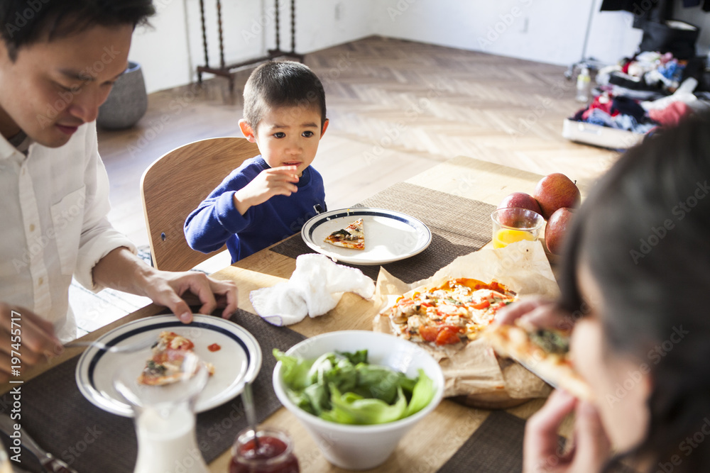 家族でピザを食べています。男の子の笑顔。